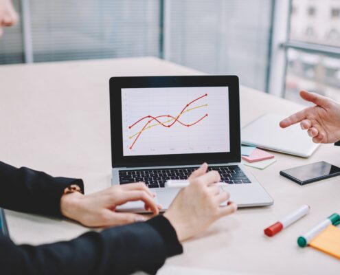 Ein Geschäftstreffen, bei dem zwei Personen mithilfe der ERP-Software Sage Datenanalysen auf einem Laptop besprechen, um Geschäftsprozesse zu optimieren