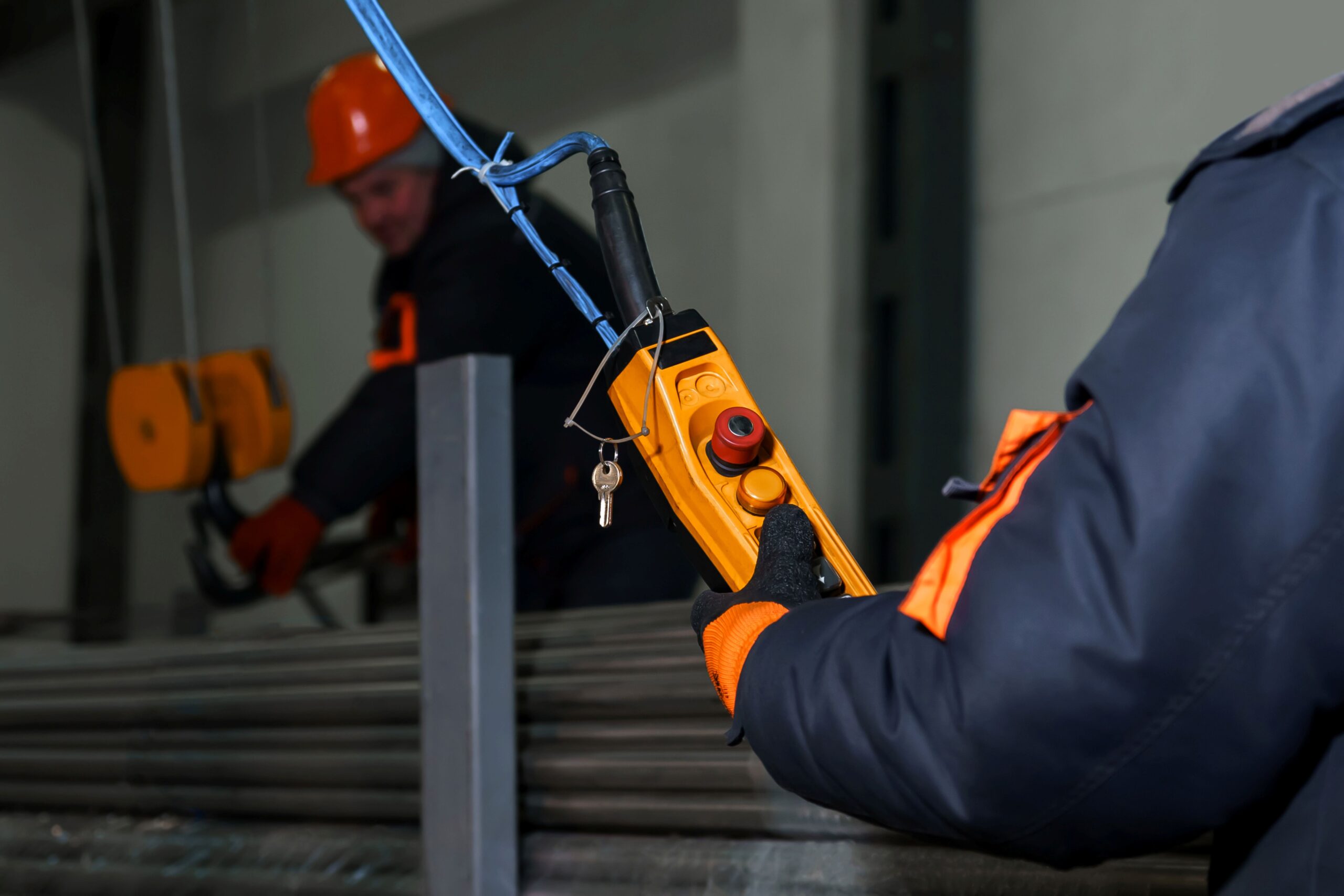 Industriearbeiter steuert einen Elektrokettenzug mit Fernbedienung