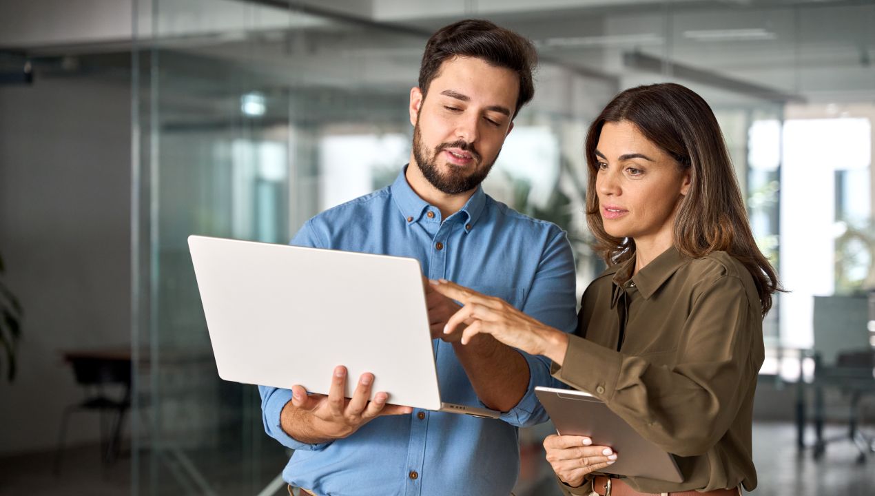 Zwei Fachkräfte analysieren Produktionsdaten auf einem Laptop und besprechen die Umsetzung einer Produktionsplanung Software im Büro