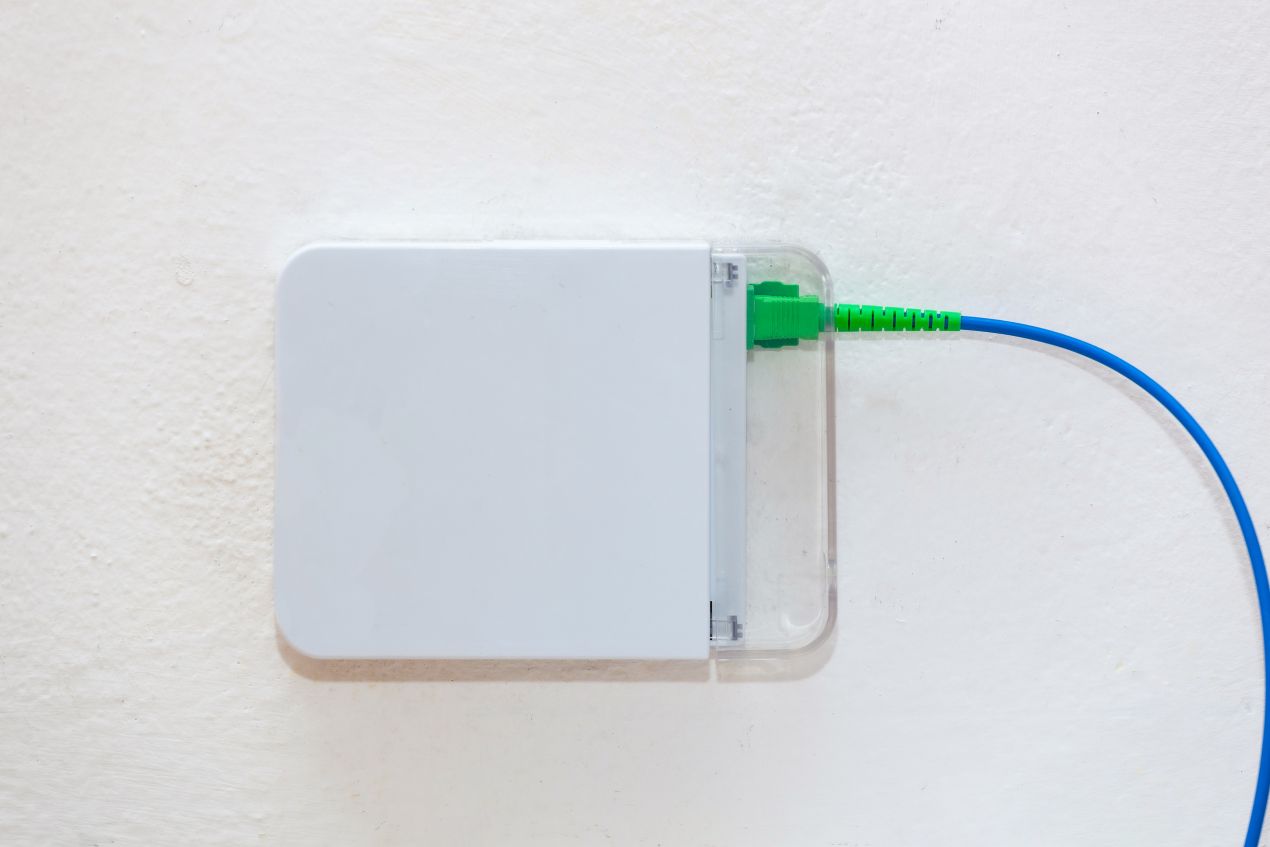 Glasfaseranschlussdose mit gruenem Stecker und blauer Leitung – Beispiel fuer installiertes FTTH Zubehoer