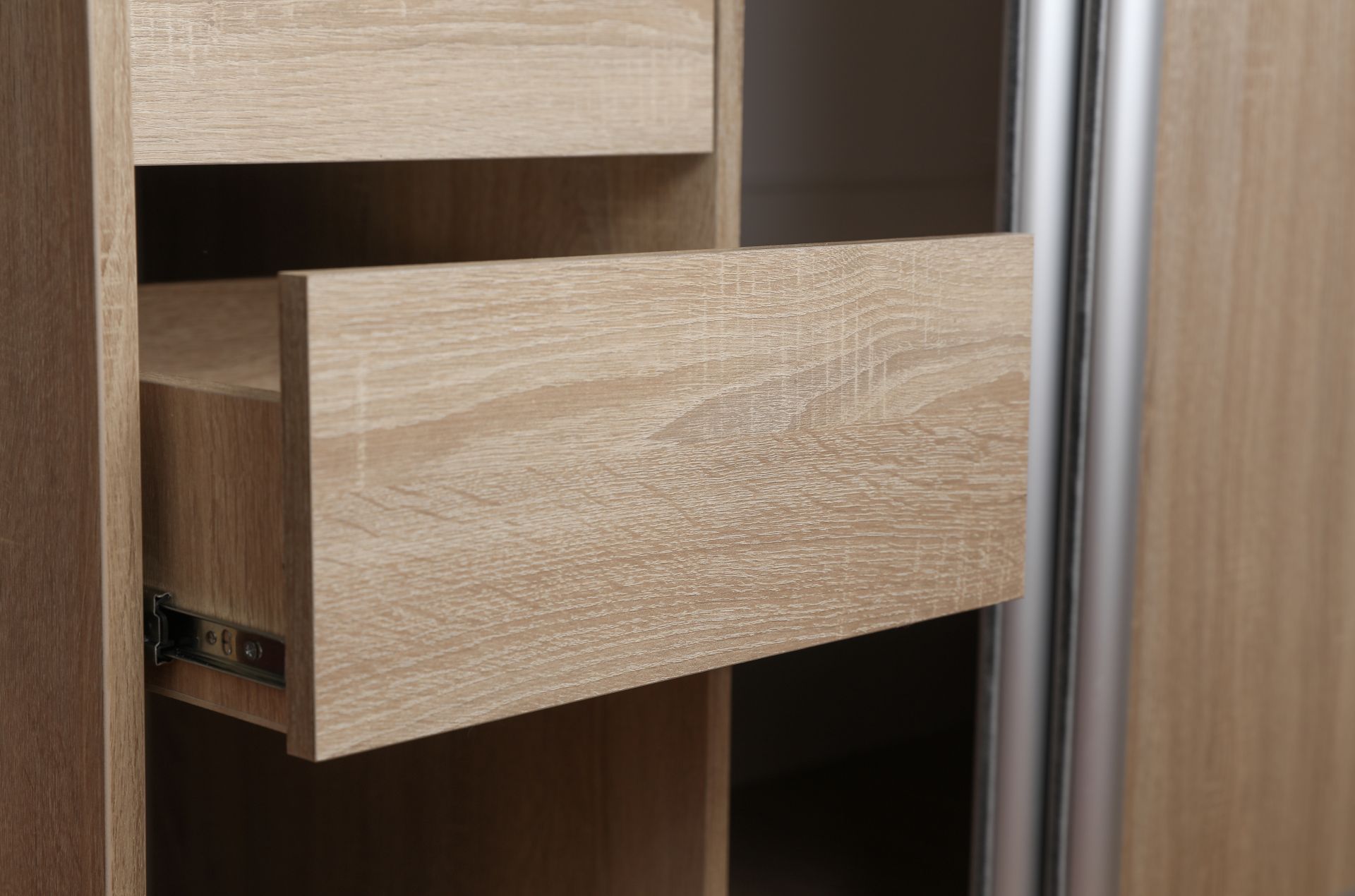 geoeffnete holzschublade in eckleiderschrank mit sichtbarer metallauszugsschiene