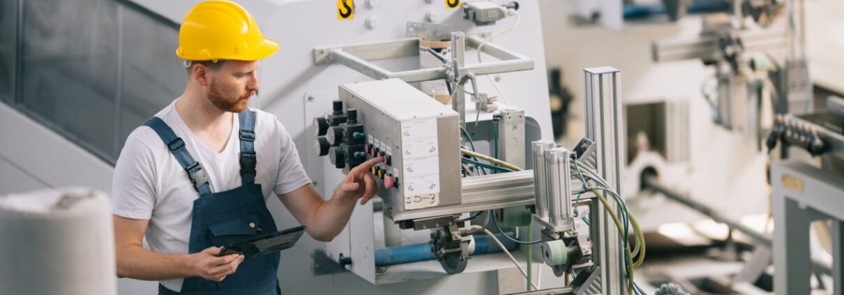 Industriemechaniker prüft Schaltung an moderner Anlage – der korrekte Anschluss am Motorklemmbrett ist entscheidend für einen störungsfreien Betrieb.