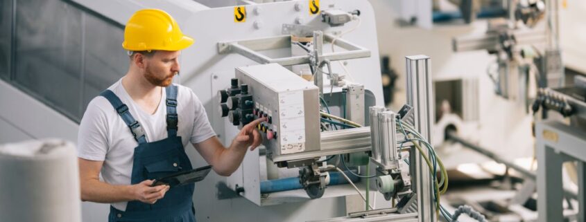 Industriemechaniker prüft Schaltung an moderner Anlage – der korrekte Anschluss am Motorklemmbrett ist entscheidend für einen störungsfreien Betrieb.