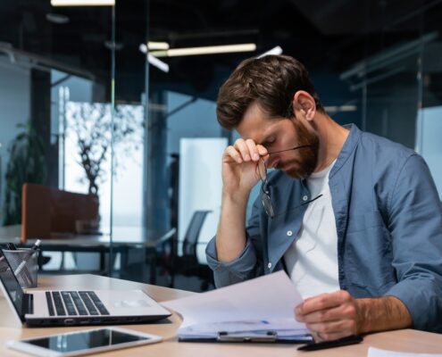 Gestresster Mann im Büro mit Unterlagen | Puck